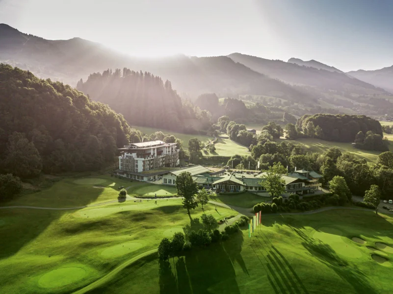 Oostenrijks landschap met laagstaande zon, met hotel Grand Tirolia Kitzbühel centraal op de foto