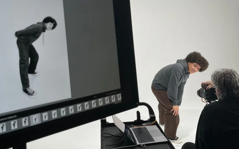 Florian poseert in een studio, terwijl er een foto van hem wordt gemaakt. Links in beeld is de gemaakte foto op een scherm te zien, rechts staat Florian in de studio.