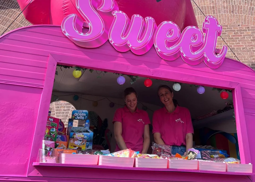 Nina staat samen met collega in een roze kraam waar zij samen snoep verkopen