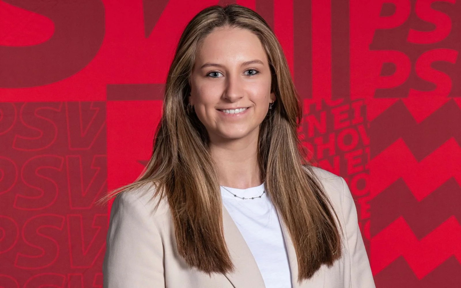 Portretfoto van Megan met een rode achtergrond van haar werkgever PSV