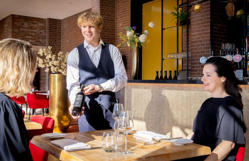 Horecastudent van De Rooi Pannen loopt met puntzakken friet uit de keuken bij Hotel Nassau.