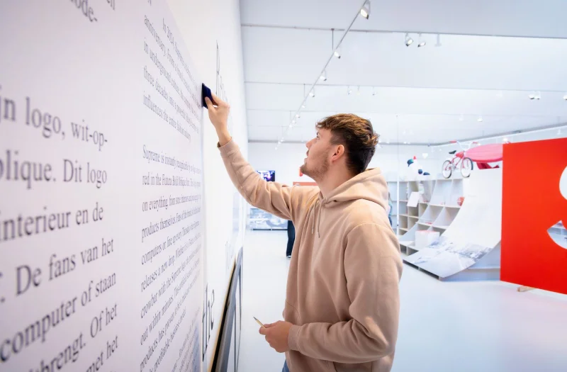 Een student van de mbo-opleiding Signspecialist van De Rooi Pannen Tilburg Vormgeving & Signmaking werkt aan de signing in een museum.