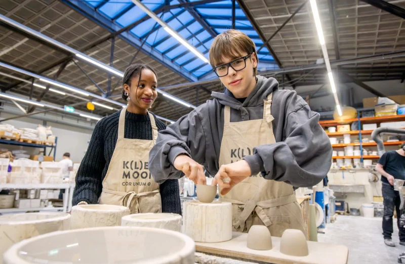 Twee studenten van de mbo-opleiding Ruimtelijk vormgever van De Rooi Pannen Tilburg Vormgeving & Signmaking aan de slag met keramiek bij Cor Unum.