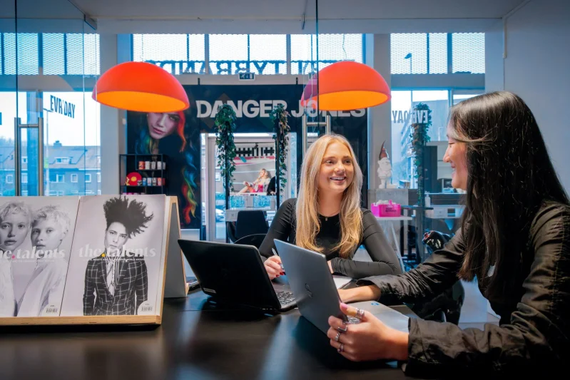 Twee studenten van de opleiding Ondernemer Webwinkel strateeg van De Rooi Pannen Tilburg Handel & Ondernemen werken samen achter hun laptops