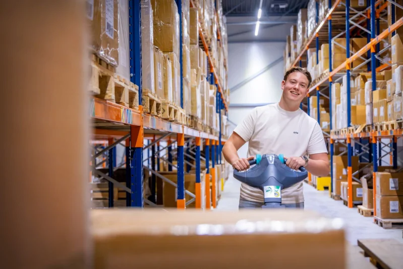 Student van de mbo-opleiding Junior manager groothandel in een distributiecentrum aan het sjouwen met kartonnen dozen.