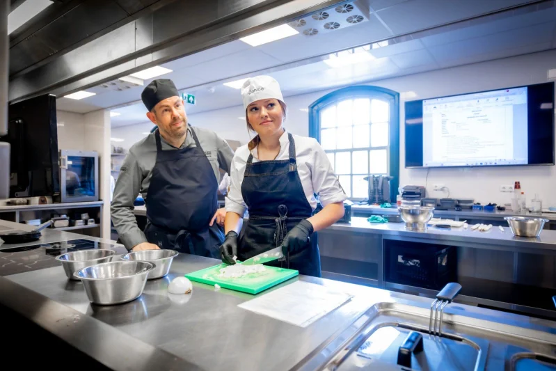 Student en docent staan naast elkaar in de keuken van De Rooi Pannen