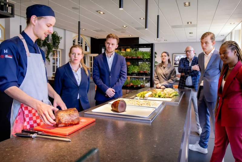 Student doet praktijkervaring op in het restaurant van De Rooi Pannen Tilburg. Hij staat een cocktail te shaken achter de bar.