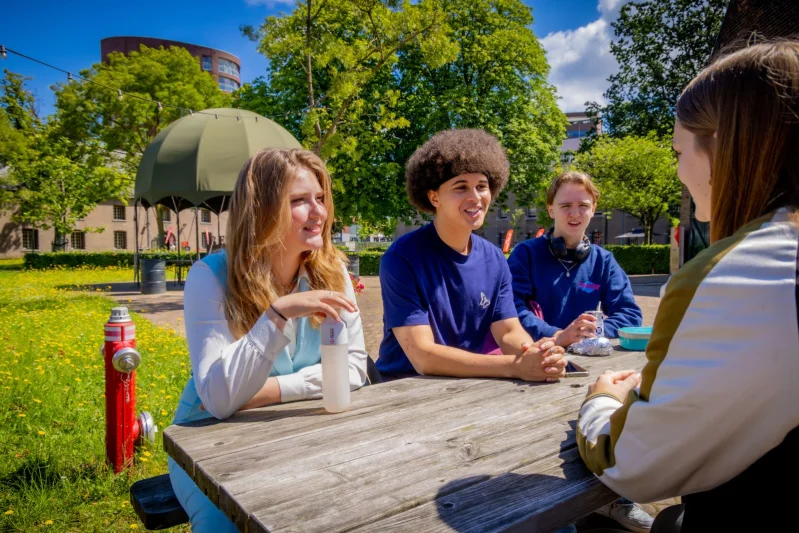 Studenten van de opleiding Leidinggevende leisure & events zitten aan tafel te praten