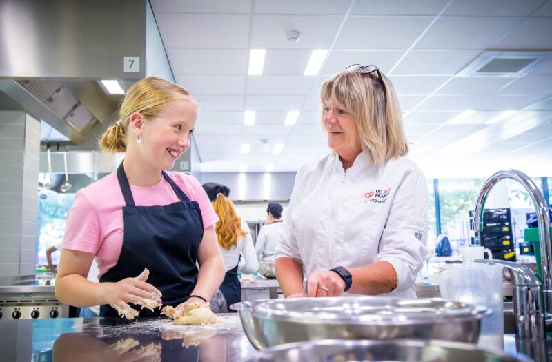 Leerling (links) en docent (rechts) in gesprek tijdens een les in de keuken van De Rooi Pannen Tilburg Vmbo.