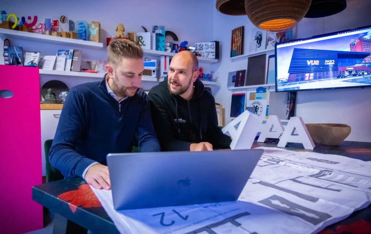 De broers werken samen achter een laptop bij Glance & Vision.