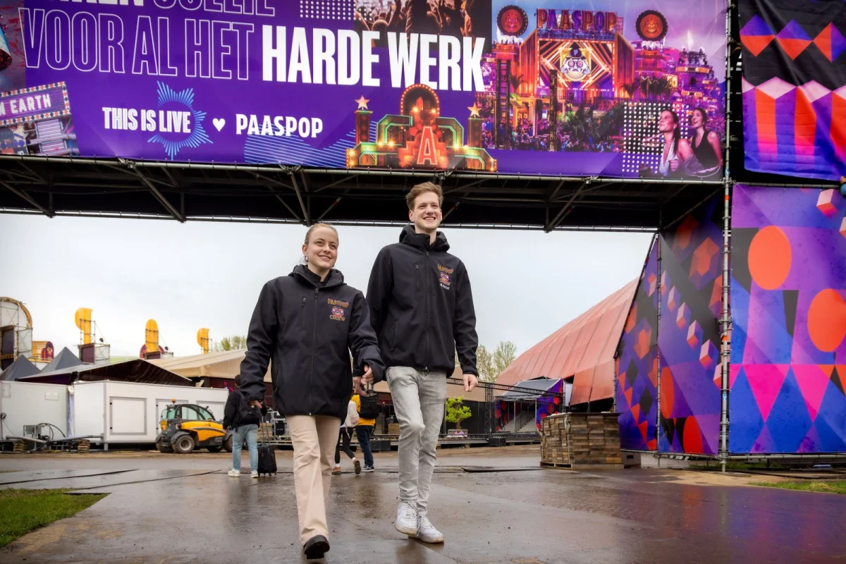 Studenten van de opleiding Medewerker evenementen lopen in crewkleding achter de schermen bij Paaspop.