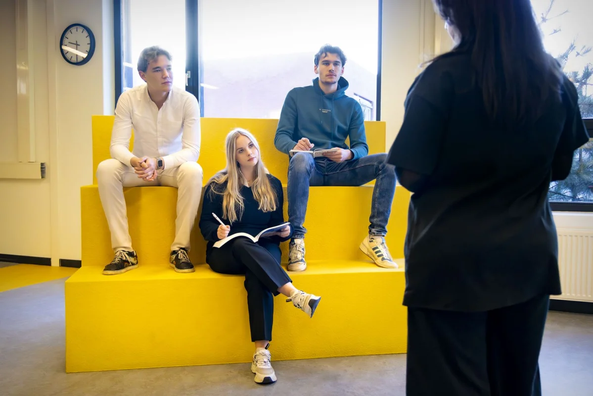 Drie studenten van de mbo-opleiding International business luisteren naar docent.