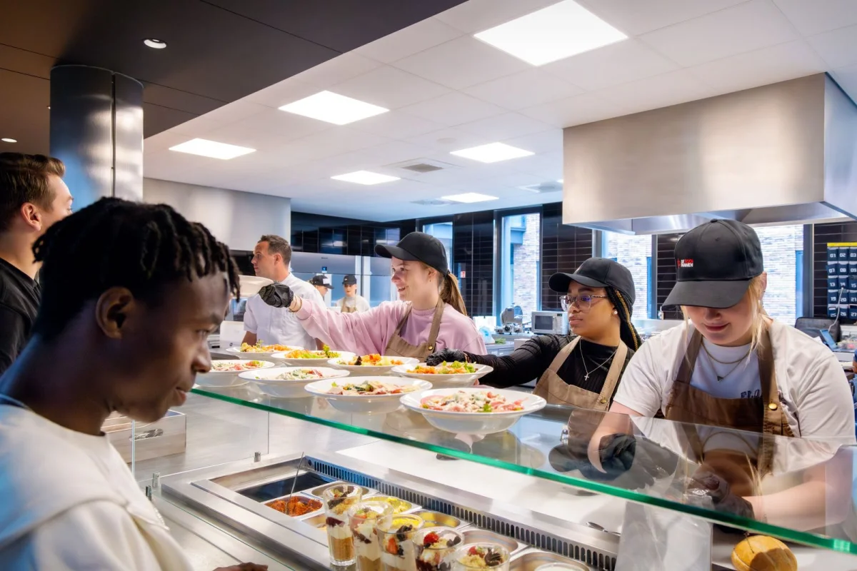 Studenten bereiden gerechten voor medestudenten in de aula van de school.