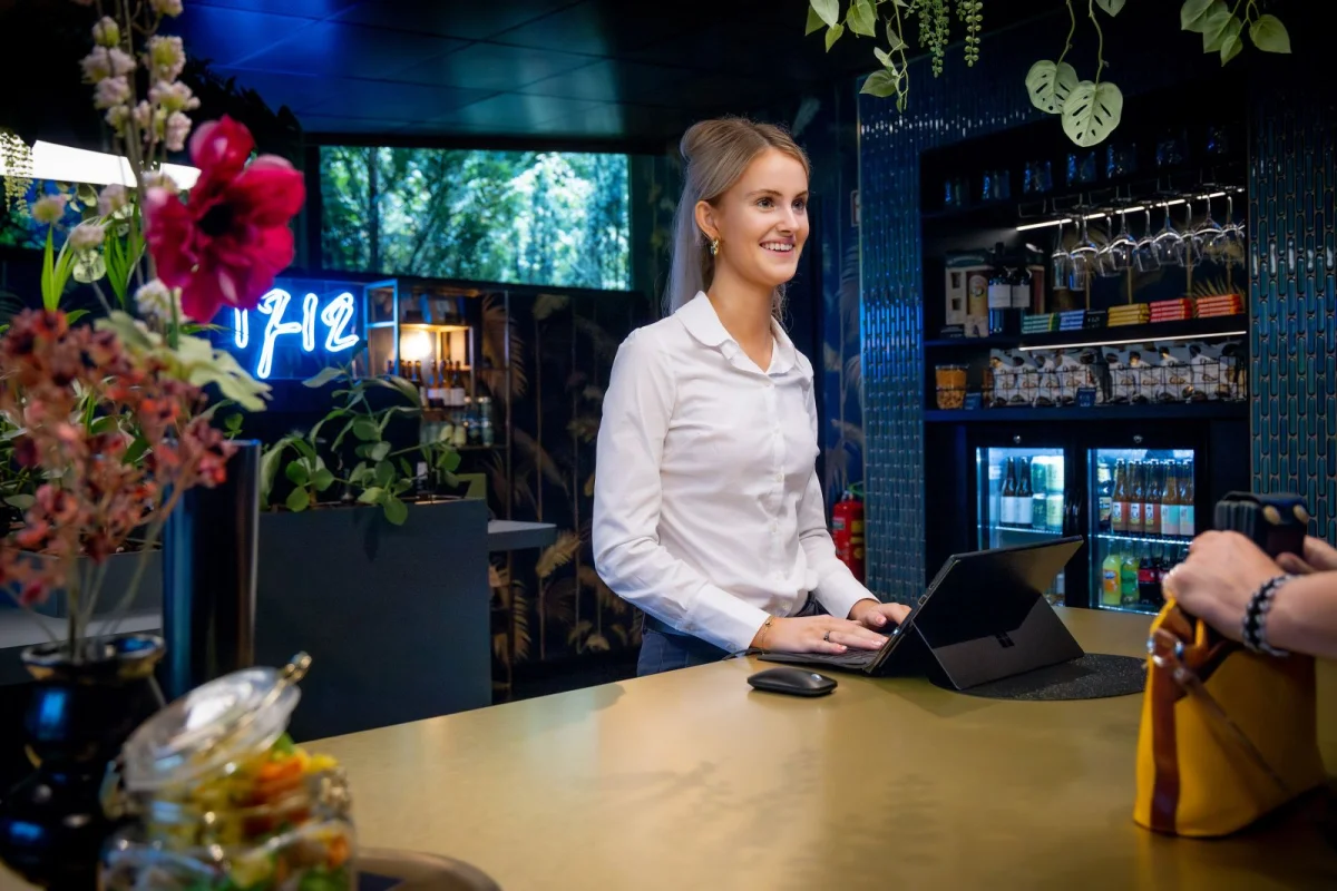 Student rekent af met een gast tijdens haar BBL-opleiding tot leidinggevende hospitality.