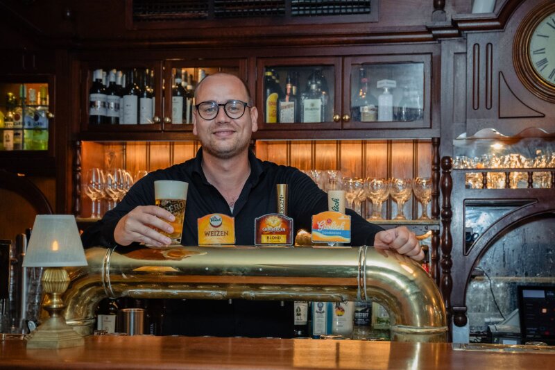 Rick Netten staat achter de bar en lacht richting de camera.